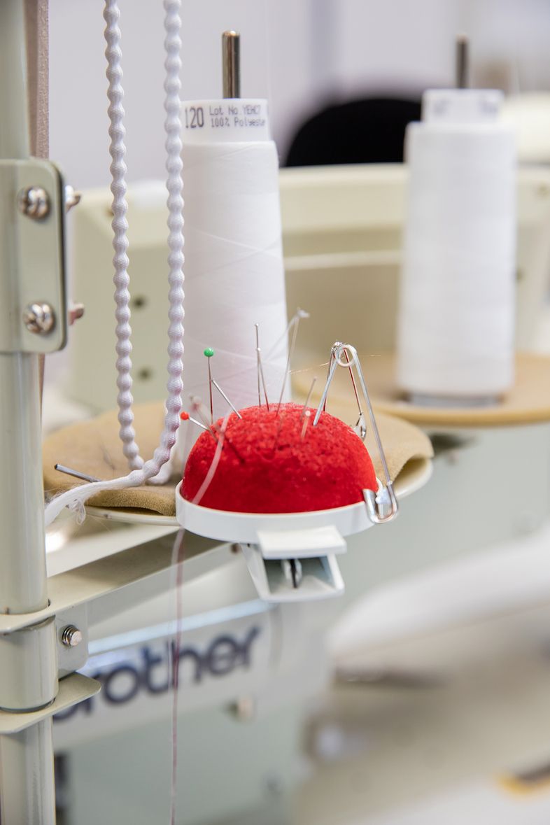 Rotes Nadelkissen mit Stecknadeln auf einer Nähmaschine