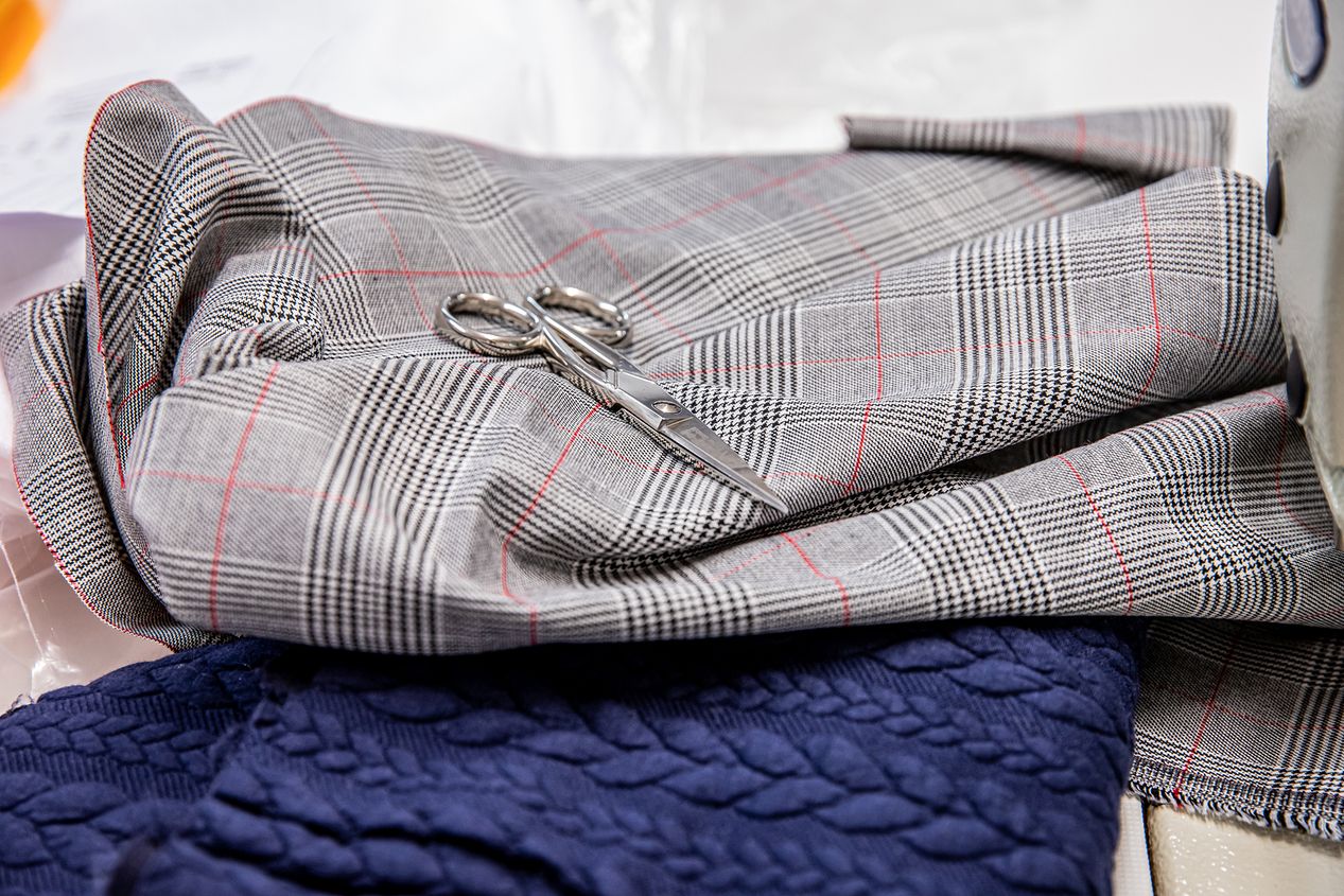Grau karierter Stoff mit einer silbernen Schere oben drauf